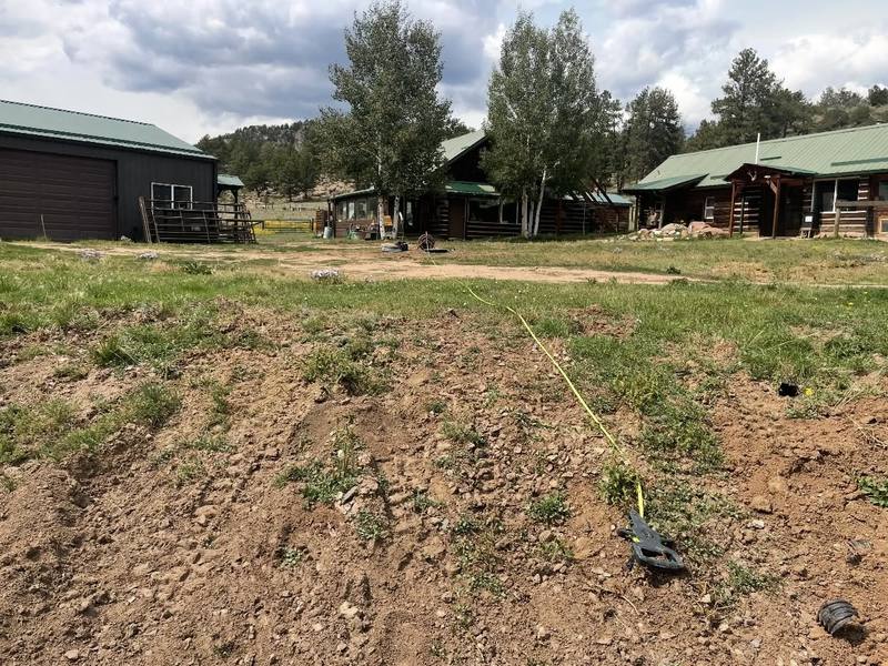Freshly dug and graded ground in front of a row of cabins after drain field work