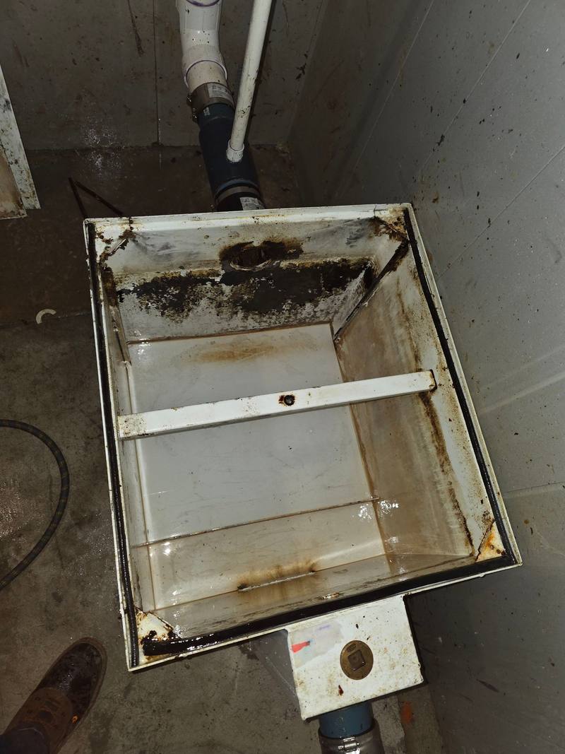 Grease interceptor box with heavy black grease buildup on its walls and rim