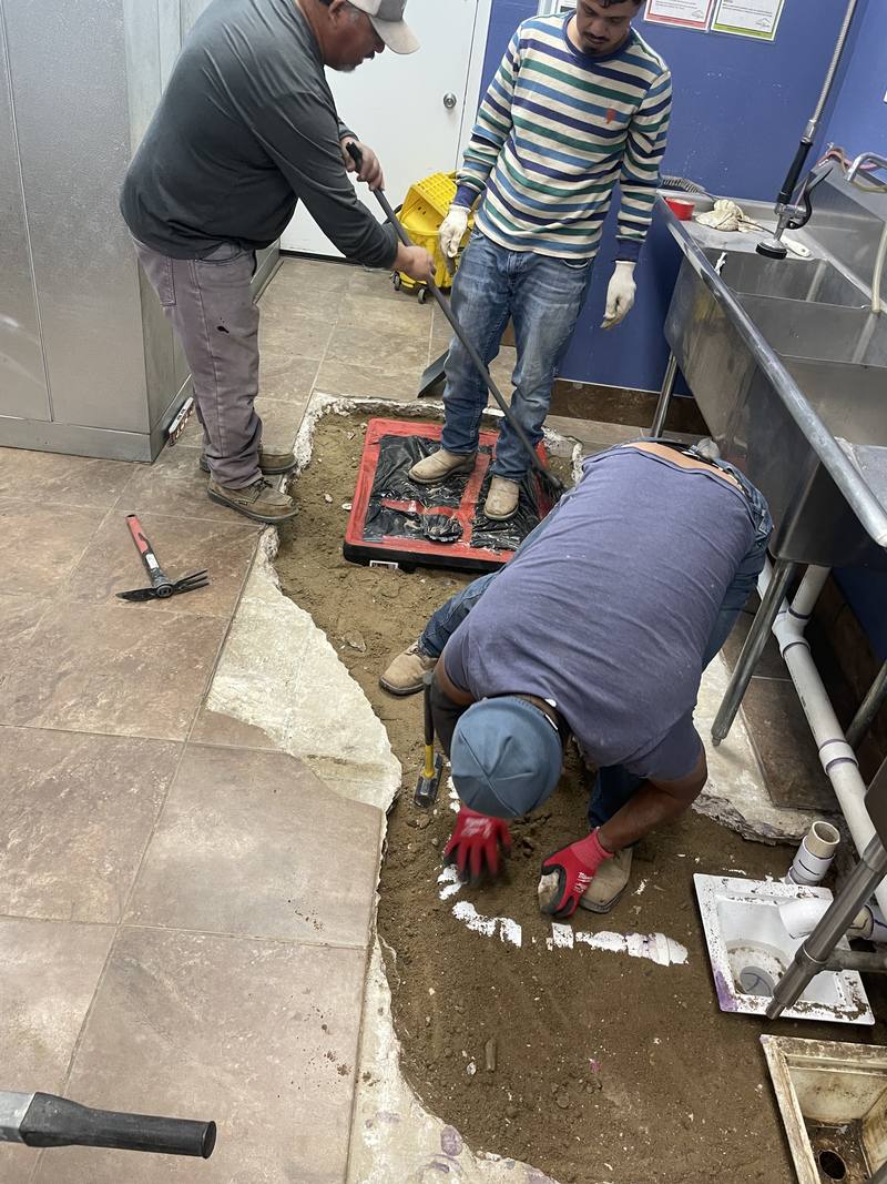 TCS crew digging around the new grease interceptor in a cut-open restaurant kitchen floor